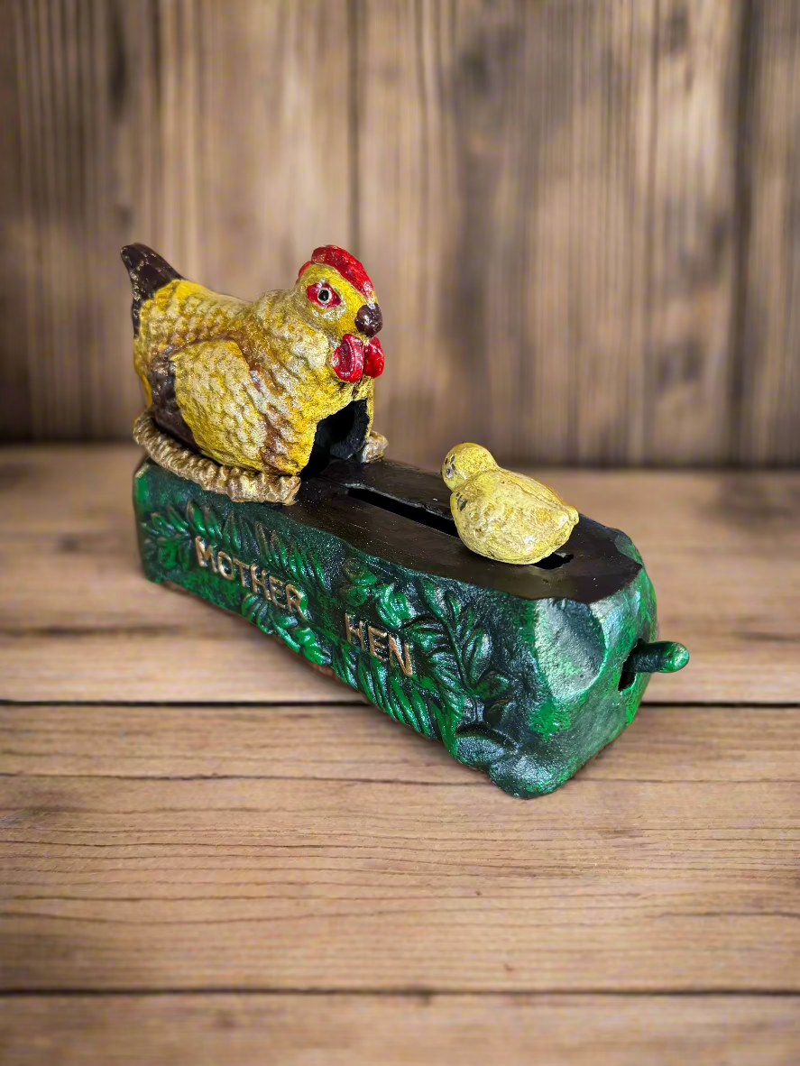 Vintage cast iron coin bank shaped like a mother hen with a chick, featuring intricate detailing and a rustic finish. A charming collectible.